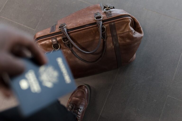 A person holding a passport with a bag on the ground.