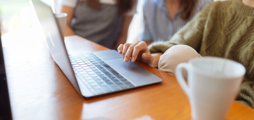 Three individuals discussing eVisa considerations on a laptop in a cozy setting with a mug of coffee nearby.