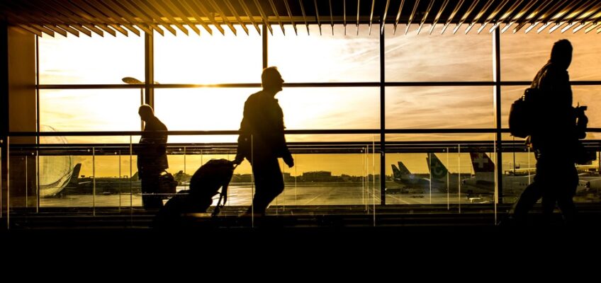 Travelers walking in an airport terminal during sunset, symbolizing the journey on an Indian eVisa.