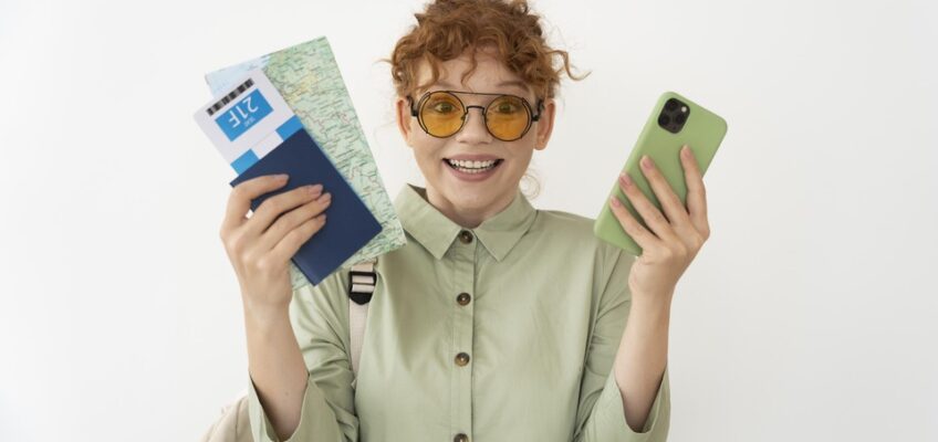 Joyful traveler holding a map, passport, and smartphone, ready to explore with sunglasses on.