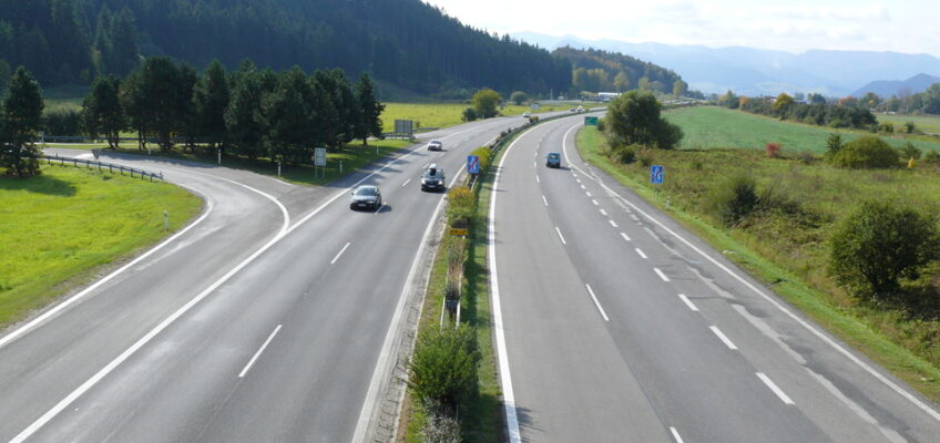 Scenic highway with cars driving through lush green landscapes, signifying land travel between borders in Europe.