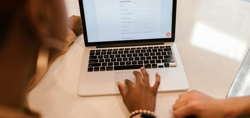 Two individuals reviewing an ETIAS application form on a laptop screen.