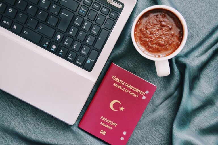 A Turkish passport placed next to a laptop and a cup of coffee, symbolizing the planning and online application process for ETIAS travel authorisation.