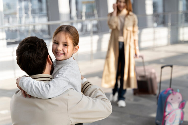 A happy child hugging her father at the airport, with her mother on a phone call in the background, and a suitcase and a pink butterfly-themed backpack indicating travel.