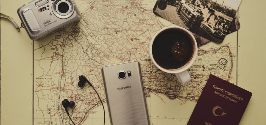 a camera, mobile phone, coffee, and passport placed on top of a map