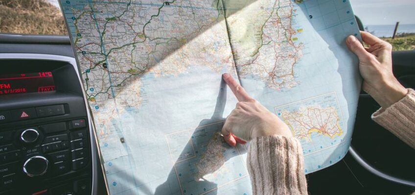 A person pointing at a certain point on a map, while being inside a vehicle