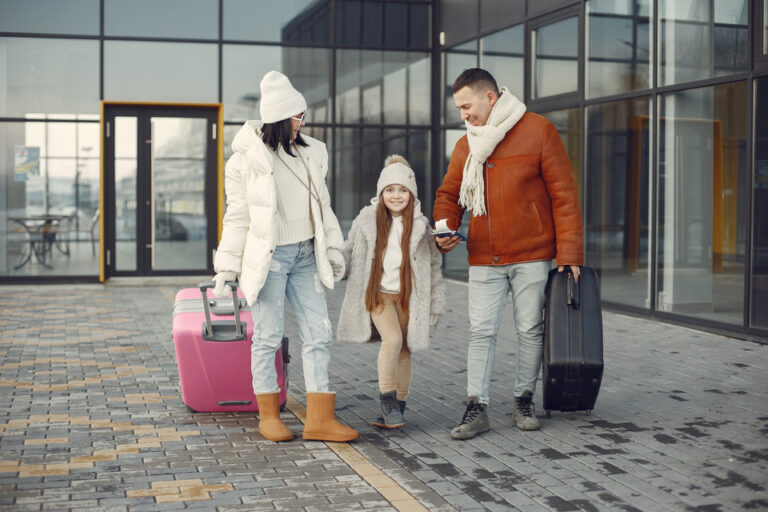 A family of three, with a child holding hands with her parents, smiles while walking outside an airport, ready for their trip, symbolizing the journey minors take when traveling to Turkey with an eVisa.