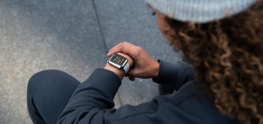 A person sitting and checking the time on a smartwatch, symbolizing time management and promptness, which are crucial when applying for a Turkish eVisa.