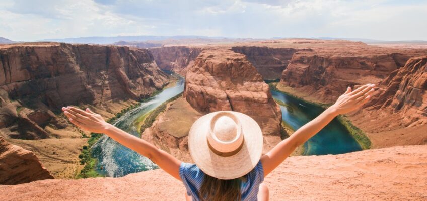 A traveler with outstretched arms facing the grandeur of Horseshoe Bend, symbolizing the freedom and exploration possible with a valid U.S. ESTA.