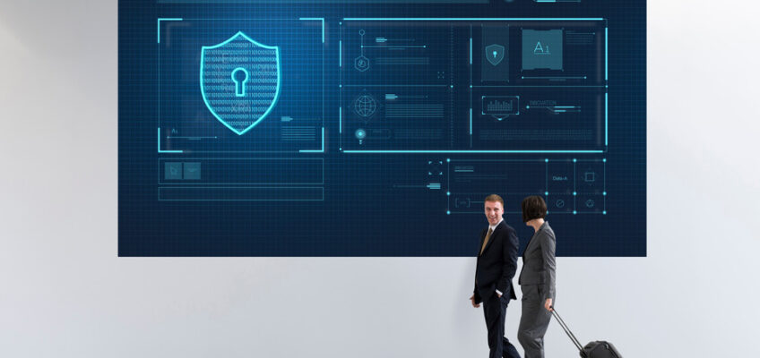 Two business travelers walking past a large digital display showing security and data analytics graphics, symbolizing the technology behind the U.S. Electronic System for Travel Authorization (ESTA).