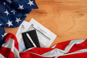 American flag draped over a wooden table with a passport, pen, and ESTA application forms on top, symbolizing the process of applying for a U.S. travel authorization.