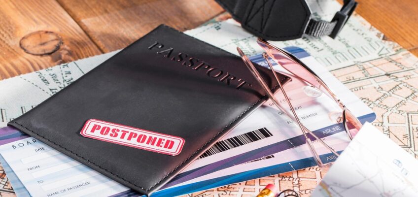 A passport in a leather cover with a 'POSTPONED' stamp, boarding passes, glasses, and a map, symbolizing potential travel delays due to common eVisa application mistakes.