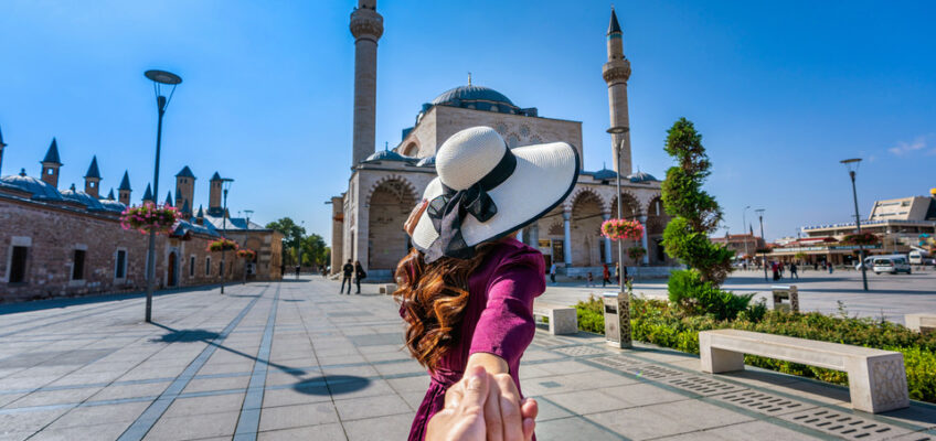 Woman holding hands with a companion, leading them towards the grandeur of a Turkish mosque, symbolizing the exploration and tourism possible with a Turkish eVisa.