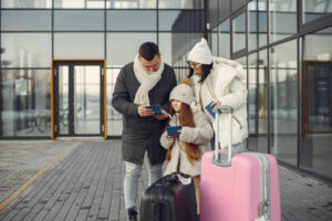 A family with a young child, dressed in winter clothes, checks their passports outside an airport, symbolizing the preparation needed for international travel with minors under the ESTA program.