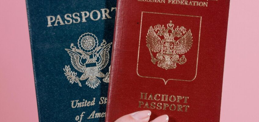 A hand holding two passports: one from the United States and the other from the Russian Federation, symbolizing individuals with multiple citizenships applying for travel authorizations.