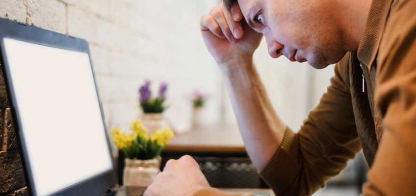 A concerned man looking at a laptop screen with a visible expression of stress and confusion, indicative of experiencing issues while trying to navigate a website.