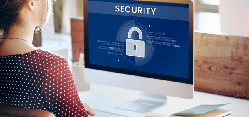 A person working on a computer with a screen displaying a digital security lock symbol, representing data protection and online security measures.