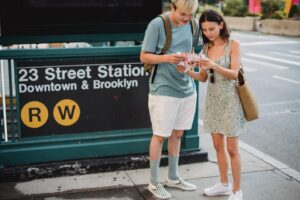 Two travelers consulting a map outside the 23rd Street Station in New York City, symbolizing the tourism aspect of permitted activities under the U.S. ESTA.