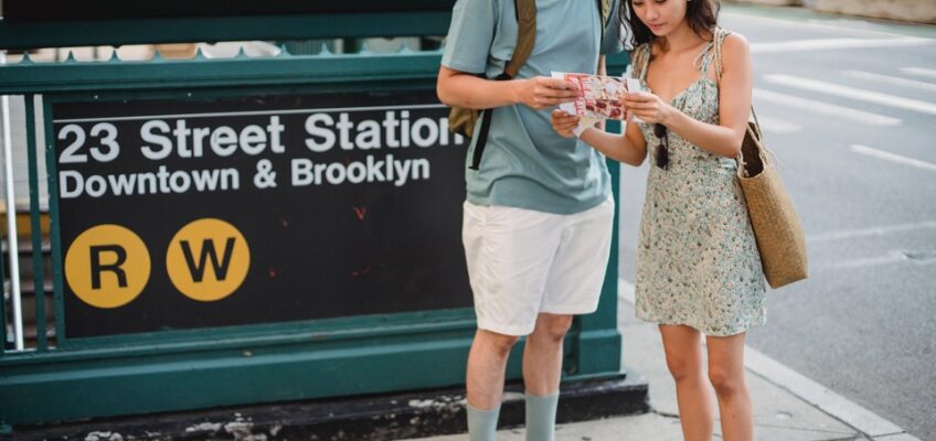 Two travelers consulting a map outside the 23rd Street Station in New York City, symbolizing the tourism aspect of permitted activities under the U.S. ESTA.