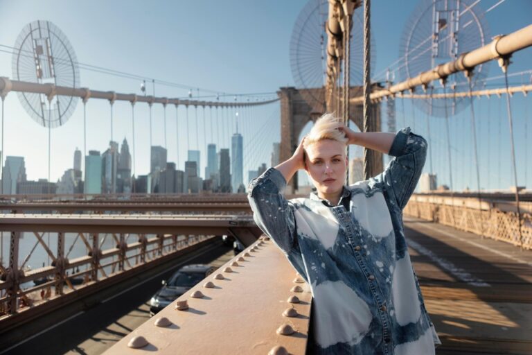 A woman stands on the Brooklyn Bridge with the New York City skyline in the background, symbolizing travel and exploration in the U.S. under an ESTA.