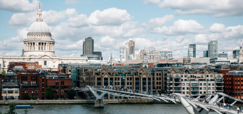 A scenic view of the River Thames with the Millennium Bridge leading towards St. Paul's Cathedral in London.