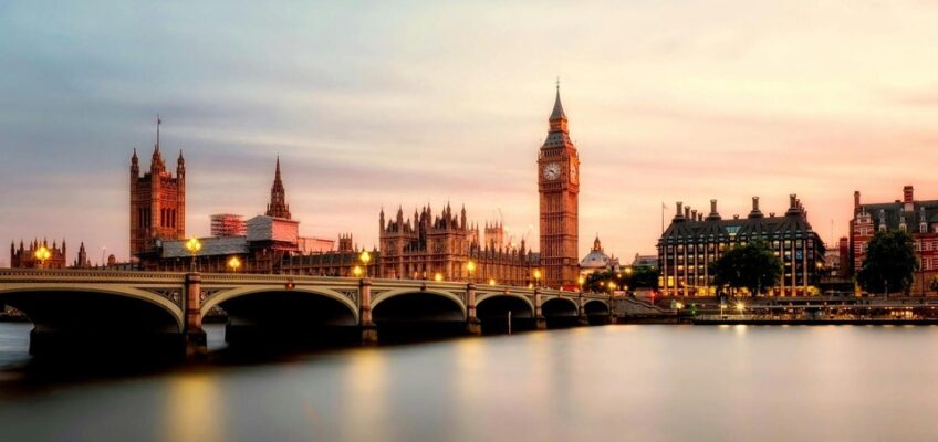 The iconic Big Ben and the Houses of Parliament beside a calm River Thames at dusk, capturing landmarks of London, the capital of the UK, where security is a key concern for visitors entering the country.