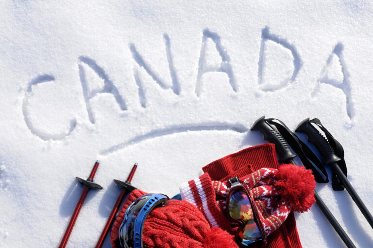 Winter scenery in Canada, with the word "Canada" written in the snow, and ski gear.