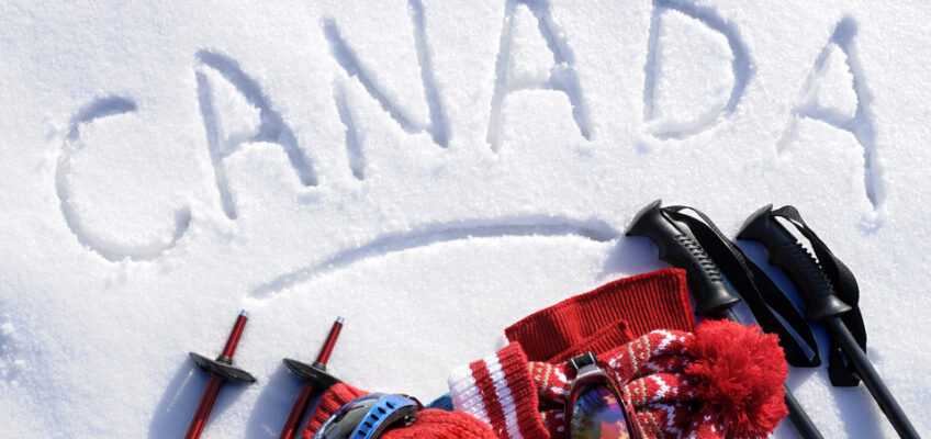 Winter scenery in Canada, with the word "Canada" written in the snow, and ski gear.