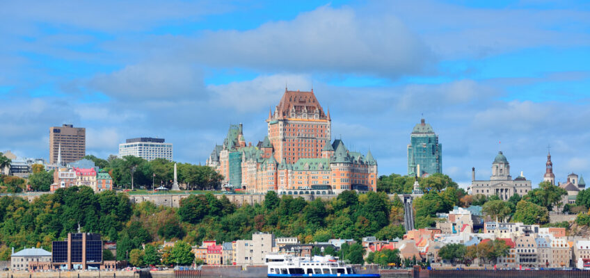 Picturesque Quebec City: Skyline reflected in the river, under a vibrant blue sky.