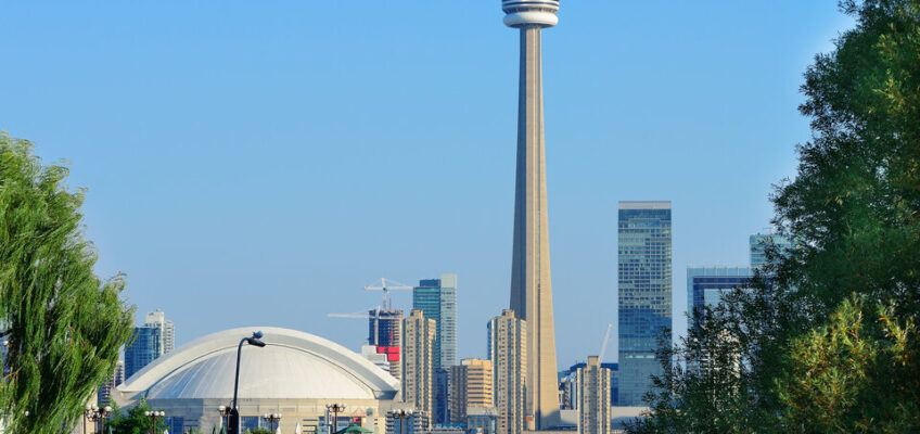 A skyline view of Toronto featuring the iconic CN Tower and the Rogers Centre.