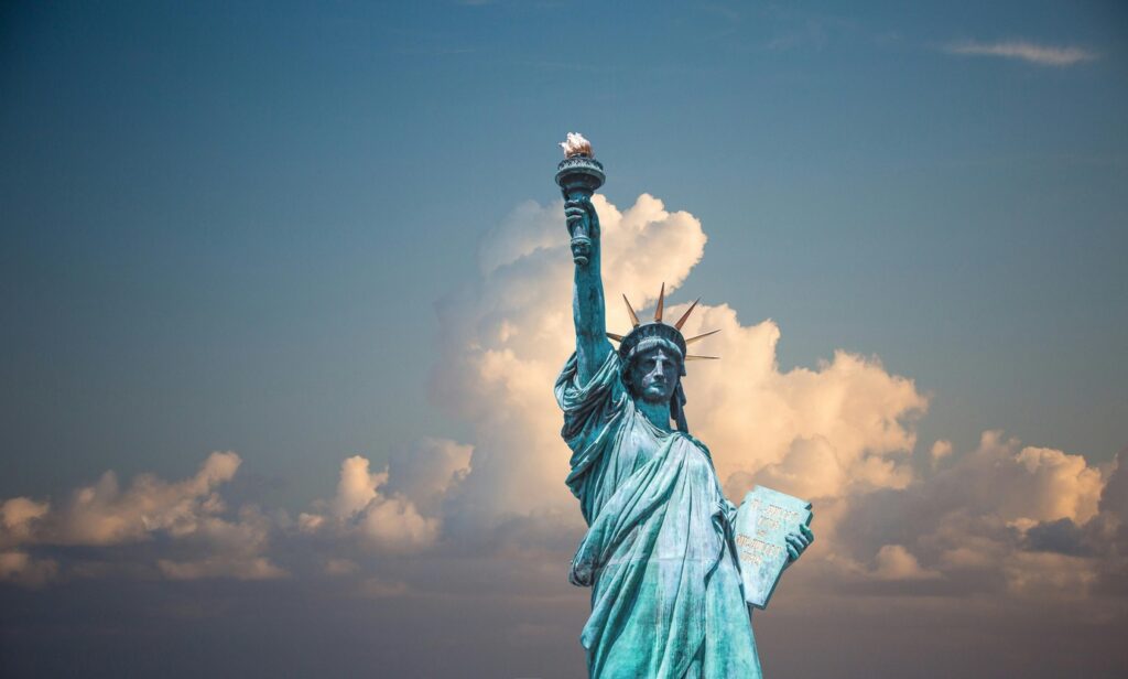 Statue of Liberty against a backdrop of a blue sky with soft clouds.
